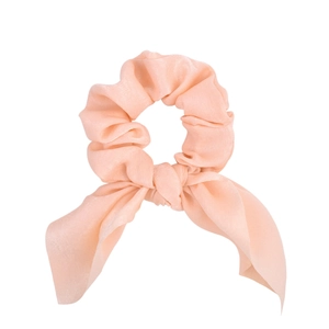 Dettaglio di scrunchie in raso rosa con lunghi nastri a fiocco su sfondo bianco puro
