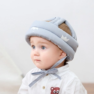 Close-up of a soft grey cotton baby safety helmet with a white crown print and chin straps