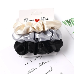 Three-piece satin scrunchie set in cream, silver, and black with smooth silky texture