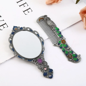 Detail of vintage peacock vanity set with enamel mirror and metal comb in retro silver
