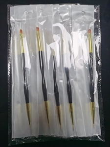 Detailed view of 5 professional black and gold nail art brushes in individual packaging