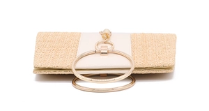 Detail of straw woven clutch with cream leather trim and gold double ring handles