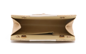 Interior view of straw woven clutch showing magnetic snaps and brown lining detail