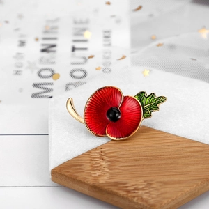 Macro shot of red poppy flower brooch with golden edges and enamel finish on stone