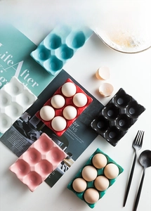 Top view of colorful six-slot ceramic egg trays in white, blue, red, black, and pink