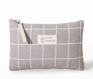 Detailed view of large capacity makeup bag with grey plaid pattern and handmade fabric label