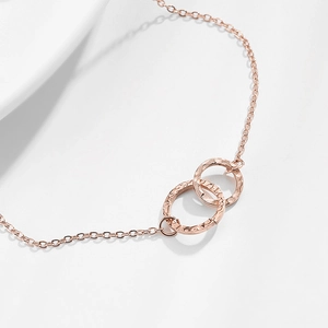 Bracelet en or rose avec deux cercles entrelacés et texture martelée sur une chaîne fine