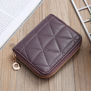 Close-up of purple quilted PU leather mini wallet with gold circular zipper on a desk