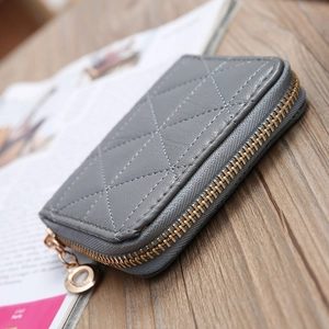 Close-up of gray quilted leather coin purse with golden circular zipper on wooden surface