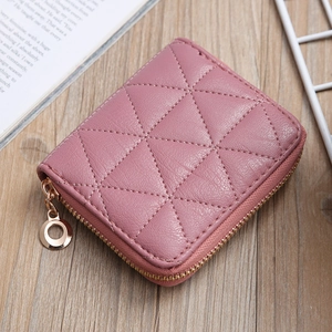 Detailed view of pink quilted PU leather coin purse with golden zipper on wooden background