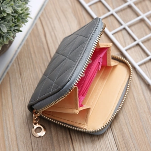 Detail view of mini gray quilted wallet with gold zipper and pink polka dot lining