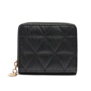Detail of black quilted leather mini wallet with gold zipper and round metal charm pendant