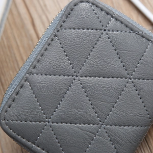 Detailed close-up of grey leather wallet featuring triangle quilted stitching and metal zipper