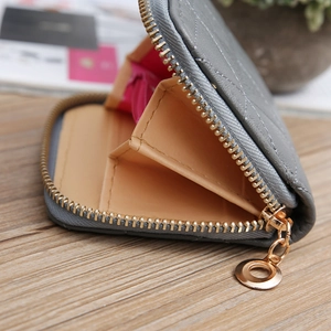 Macro detail of grey quilted wallet showing internal brown compartments and gold zipper