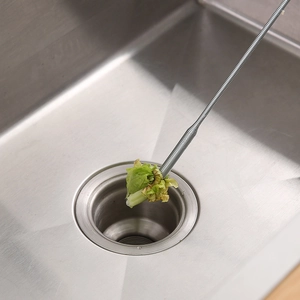 Flexible stainless steel drain cleaner tool grabbing debris from a kitchen sink drain