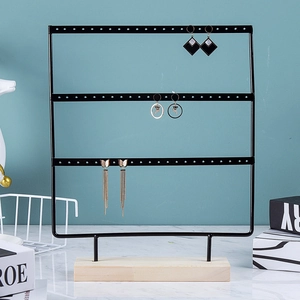 Detailed view of 3-tier black metal earring organizer with a natural pine wood base