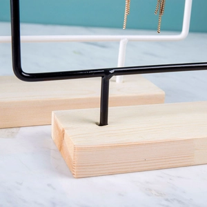 Close-up of wooden base and metal frame detail on minimalist earring display stand