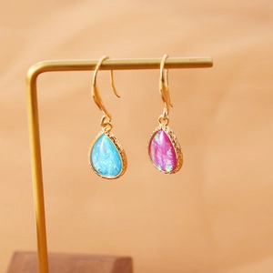 Macro shot of gold teardrop earrings with iridescent blue and purple faux opal stones