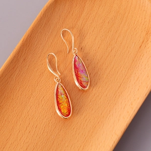 Detail of teardrop earrings with red and yellow iridescent foil set in gold plating