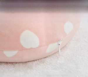 Detail of the hidden zipper design on a pink plush neck pillow with heart patterns