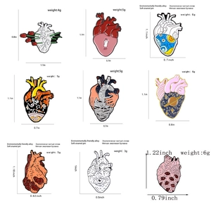 Macro view showing 9 artistic anatomical heart enamel pins with starry sky and flower designs