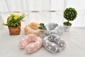 Detailed view of U-shaped memory foam neck pillows in four pastel colors with bow patterns