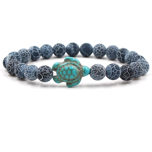 Close-up of white turquoise bead bracelet featuring a detailed turquoise turtle charm