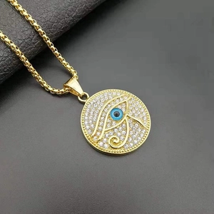 Macro detail of gold plated Eye of Horus pendant with blue stone and inlaid crystals