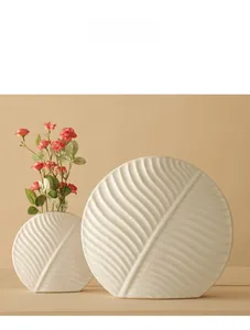Close-up of matte white ceramic vase with leaf vein texture and minimalist round shape