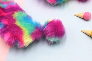 Dettaglio macro della trama in ecopelliccia arcobaleno e del pompon soffice dell'astuccio