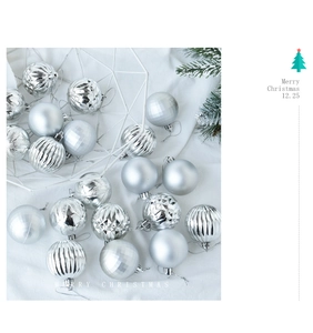 Close-up of assorted silver Christmas balls with matte and glossy textures on white fabric