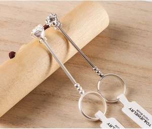 Detail of silver rose flower cigarette holder ring with hand-made tag on wood stand