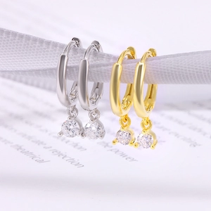 Detail of silver and gold S925 earrings with heart and arrow zircons on white ribbons