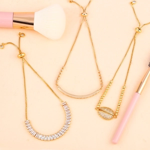 Adjustable gold bolo bracelets featuring zircon stones and shell design on peach background