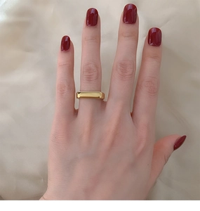 Detailed view of wide 18K gold plated rectangular signet ring on a finger with polish finish