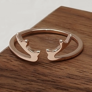 Bague ouverte élégante en or rose motif bois de cerf sur une surface en bois