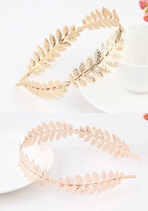 Detailed view of Greek style gold and rose gold metal leaf headbands on white background