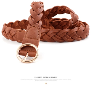 Gros plan sur la texture d'une ceinture tressée marron avec boucle ronde en métal doré