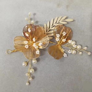 Detailed close-up of golden handmade bridal hairpiece with pearls and wire-wrapped flowers