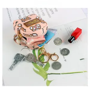Pink cartoon bear coin purse with zipper closure and pearl puller on a magazine background