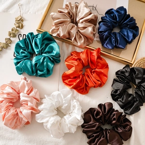 Elegant satin silk scrunchies set in various colors shown in a flat lay arrangement