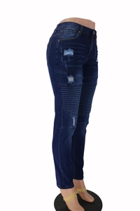 Close-up of distressed ripped details and pleated texture on dark blue skinny jeans