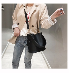 Detail of black matte leather bucket bag with wide handle and gold metal hardware
