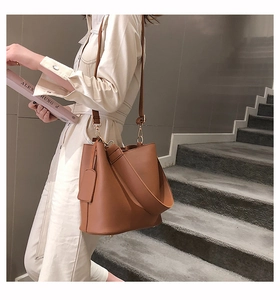 Detail view of brown PU leather bucket bag featuring decorative tag and golden metal hardware