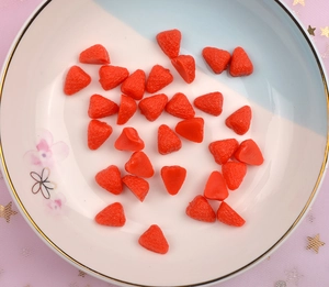 Close-up of realistic resin strawberry charms for DIY crafts and phone case decoration