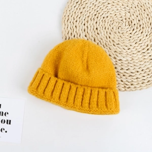 Detail of yellow knit beanie with soft wool texture and classic ribbed cuff on a flat lay