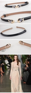 Detail of adjustable black patent leather belt with golden fish buckle and dark grey gem