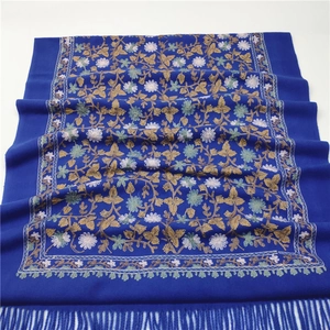 Detail of dark blue scarf with intricate floral embroidery and decorative fringes