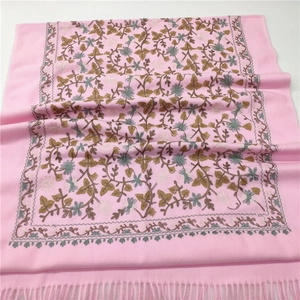 Detail of pink cashmere-like shawl featuring intricate floral embroidery and fringe tassels
