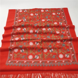 Close-up of red shawl with elegant floral embroidery and soft tassel fringe details
